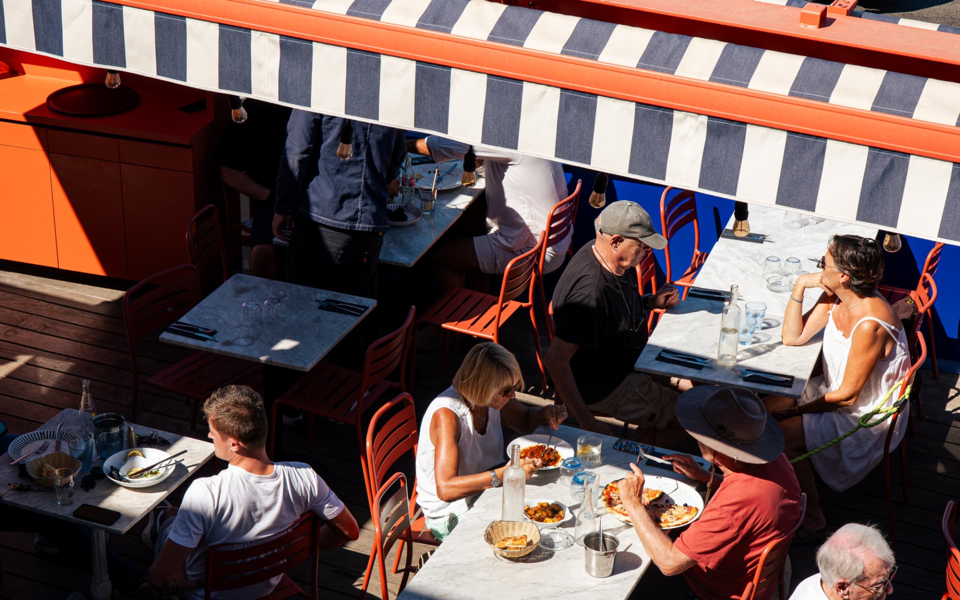 Vue plongeante sur la terrasse animée du Lou Mar sous les stores rayés