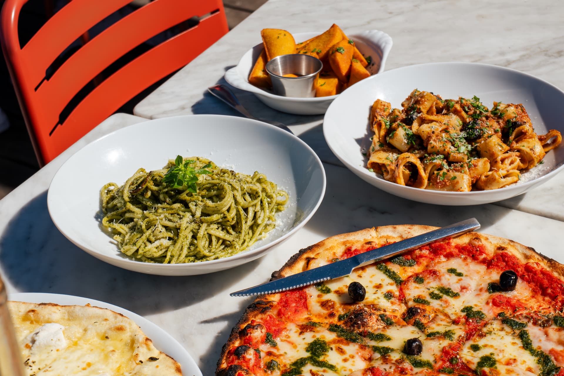 Table garnie de linguine au pesto, calamarata, panisses et pizzas