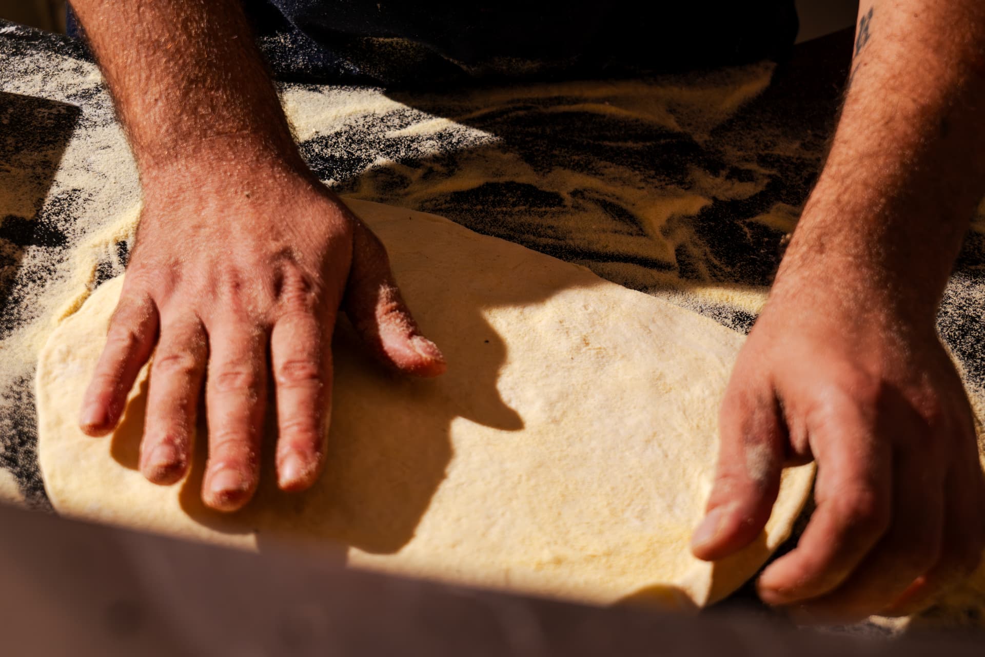 Le pizzaïolo étalant la pâte à la main