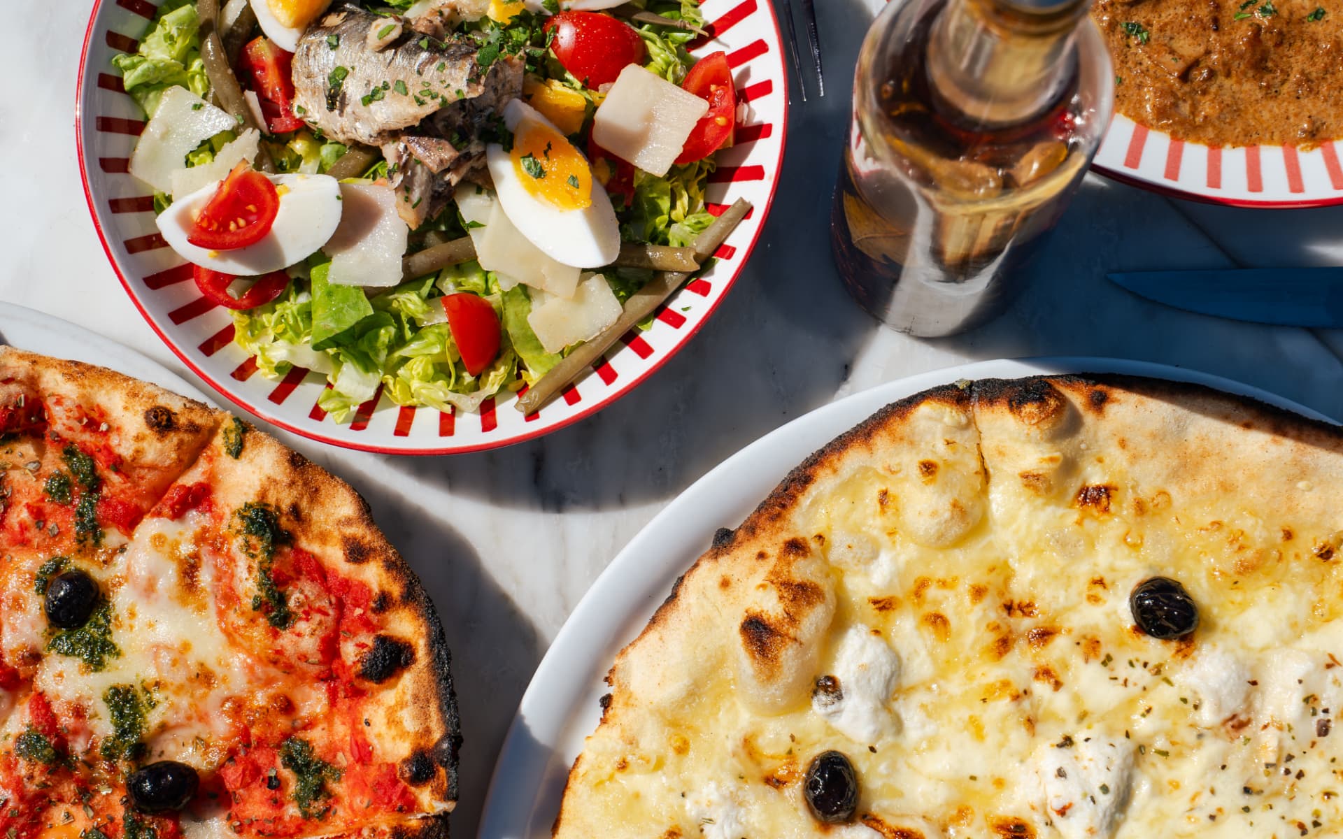 Deux pizzas au feu de bois et la salade marseillaise vues du dessus